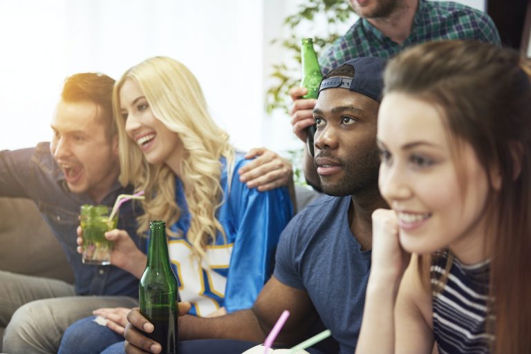Group of young people in student accommodation watching soccer match